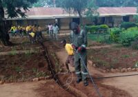 Laying down fiber cable in African village